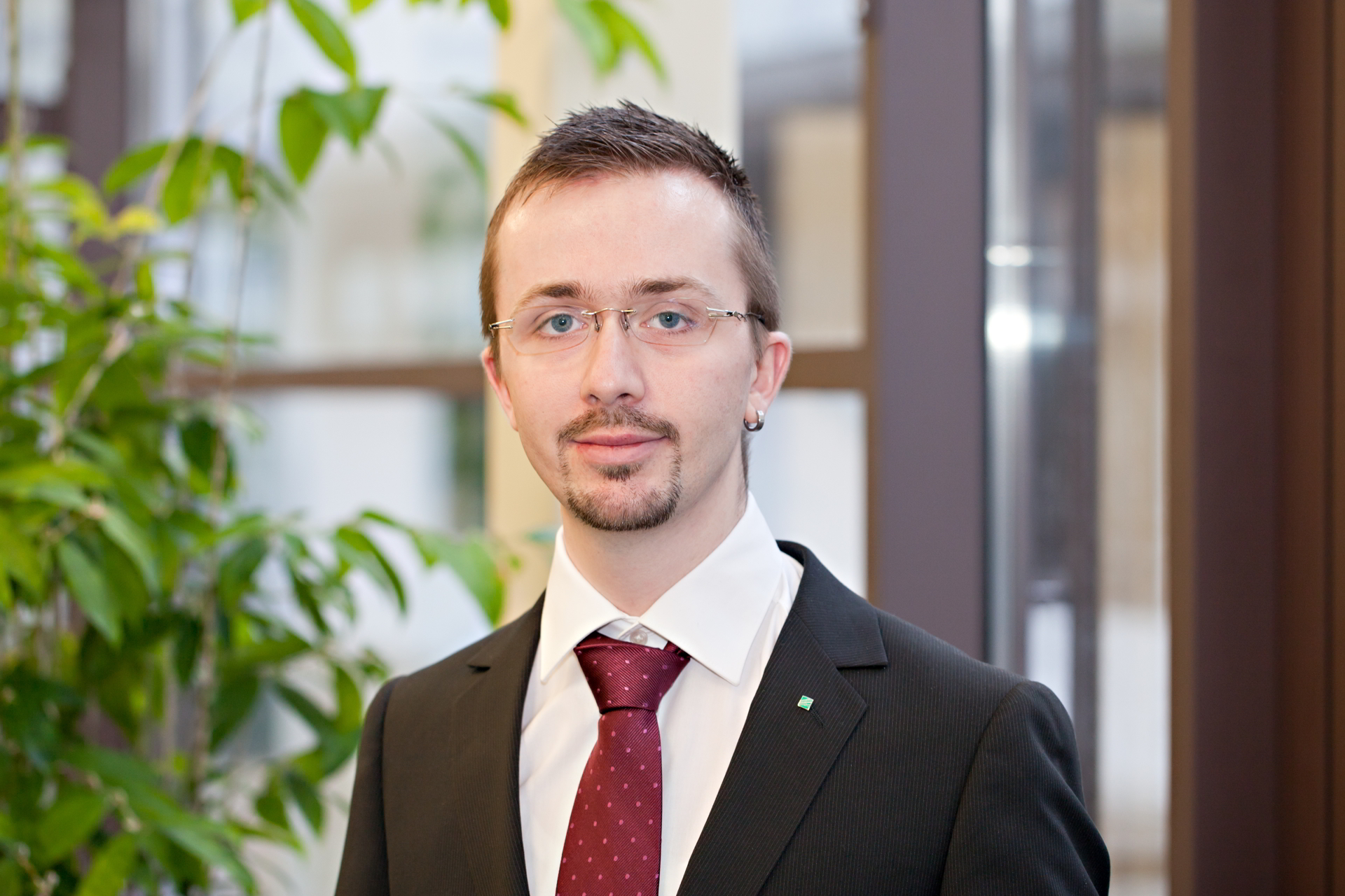 Portrait of young man in suit in front of blurred glass front